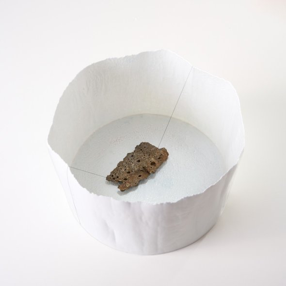 eine weißes hauchdünnes Porzellan Gefäß mit einem Stein drin liegend