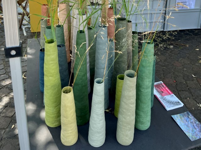 hohe schlanke Keramikvasen in verschiedenen Grüntönen mit Gräsern in den Vasen