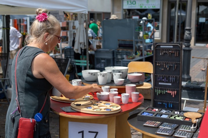 eine Keramikerin steht vor ihrem Stand und sortiert ihre Keramiktassen