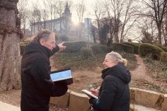 Mann spricht mit Frau über Skizzen, im Hintergrund der Michaelsberg